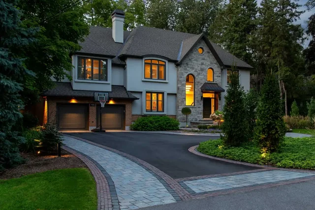 A paver driveway and lit entrance at dusk.
