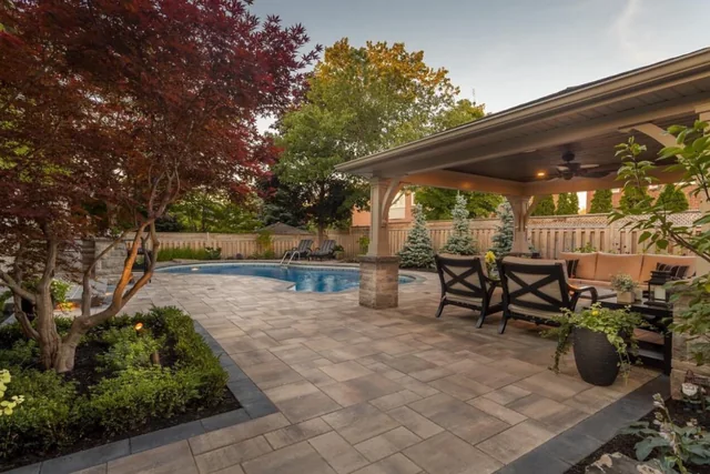 A covered pavilion and paved patio beside a pool.